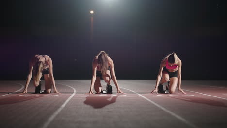 Front-view-zoom-camera-three-women-in-the-stadium-at-night-in-slow-motion-start-and-run-to-the-camera